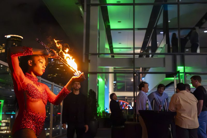 A dancer spins a flaming torch to entertain guests at Allen Porter's extravagant unveiling party for his patented, legal cannabis-infused drink at Ventanas rooftop, Atlanta, GA, on March 9, 2024. (Olivia Bowdoin for the AJC).