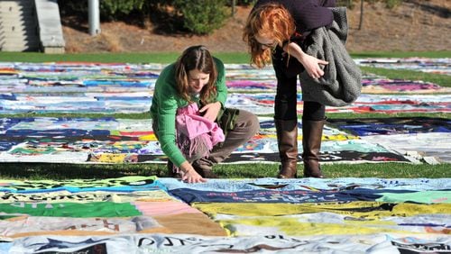 Kate Ogorzaly (left) touched one of AIDS Memorial Quilt displays as Ogorzally and Meg Bertram, then both graduate students majoring Global Health, stop for a closer look in 2011 at the AIDS Memorial Quilt at Emory University’s McDonough Field. Hyosub Shin, hshin@ajc.com