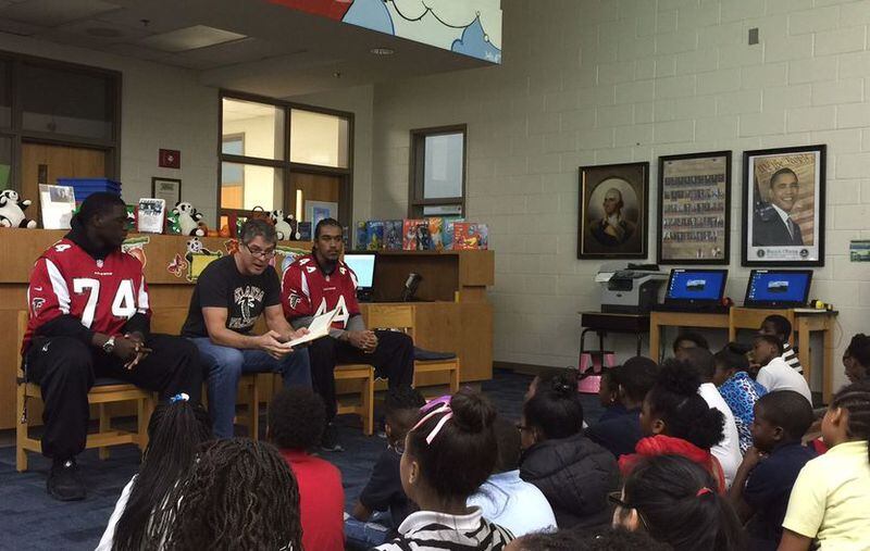 Former Atlanta Falcons defensive end Tim Green, center, flanked by current players Joey Mbu, left, and Vic Beasley Jr., reads to students at Parkside Elementary in Atlanta. MARLON A. WALKER/marlon.walker@ajc.com