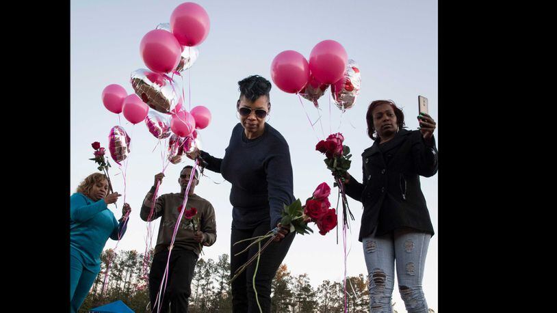 Akiyoshi Metts, center, lays roses on her mother's grave (marked by an orange marker) along with her siblings, on her mother's (Renee Metts) birthday, Monday, Nov.13, 2017 in Palmetto, Ga. Fulton County is terminating a contract it had with Morehouse School of Medicine to provide medical care for its inmates. Jail officials attribute at least five inmate deaths to that sub-par care.