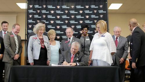 Surrounded by school officials and legislators, Gov. Nathan Deal signed this year’s budget at Lanier High School in Buford. The state budget included the first major pay raises for 200,000 teachers and state employees since before the Great Recession. BOB ANDRES / BANDRES@AJC.COM