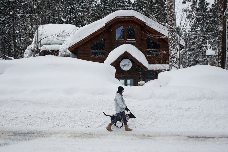 FILE - Laurene Bishop, from South Lake Tahoe, walks her dog Aubrey down Ski Run Boulevard in South Lake Tahoe, Calif., March 1, 2023. A new study finds the snow deluge in California, which quickly erased a two decade long megadrought, was essentially a once-in-a-lifetime rescue from above. The study authors coined the term “snow deluge” for one-in-20-year heavy snowfalls. (Salgu Wissmath/San Francisco Chronicle via AP, File)