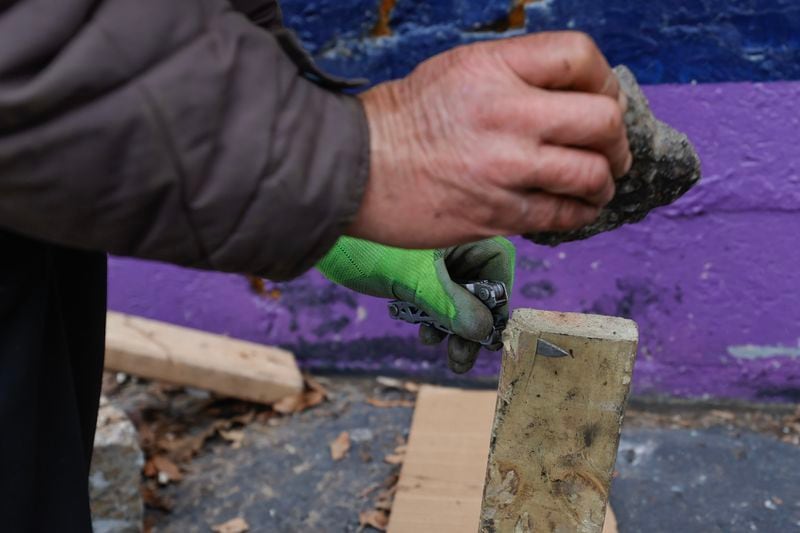 Will Bittler, who has been homeless for about five months, demonstrates how he uses his pocket knife and a rock to cut pieces of wood for fire on Friday, December 29, 2023. (Natrice Miller/ Natrice.miller@ajc.com)