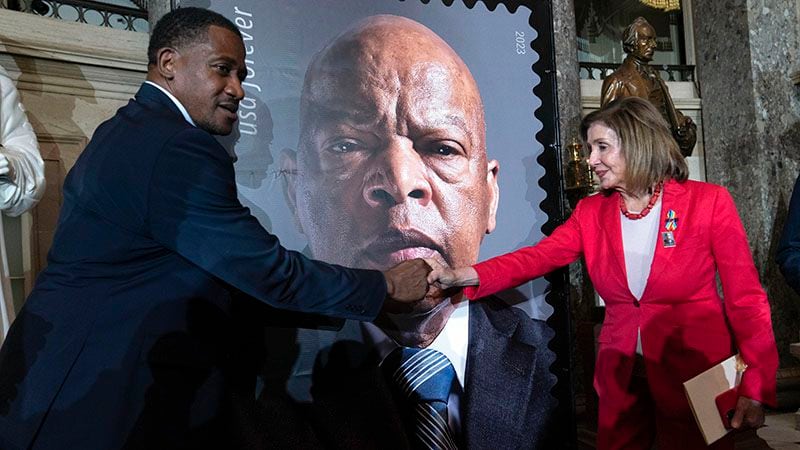 Michael Collins, a former aide to U.S. Rep. John Lewis, shakes hands with former U.S. House Speaker Nancy Pelosi during a ceremony last month in Washington to mark to reveal the design of a stamp honoring Lewis. (AP Photo/Jose Luis Magana)