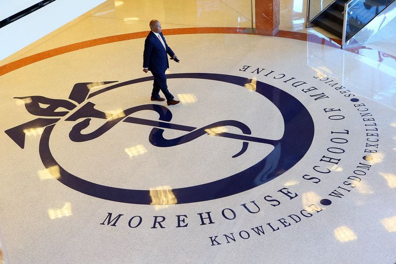 Dr. Louis W. Sullivan, the founding dean and first president of Morehouse School of Medicine, walks across the school logo in the lobby of the building bearing his name, the Louis W. Sullivan National Center for Primary Care, during a visit in 2014. CURTIS COMPTON / CCOMPTON@AJC.COM