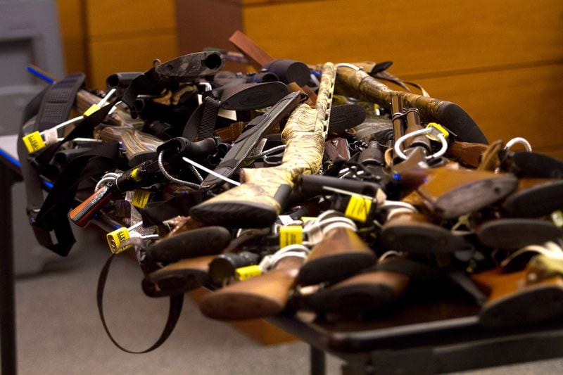 Tex McIver’s dozens of guns are piled onto table in court on Day 12 of McIver’s murder trial. Steve Schaefer / For the AJC