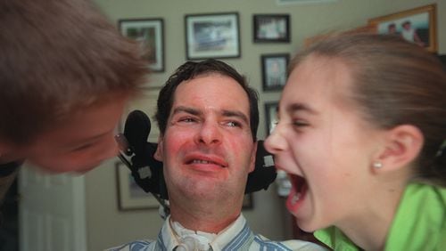 David Jayne, who has had ALS (aka Lou Gehrig's disease) for 12 years, musters his biggest smile after getting kisses on the cheek from children Hunter, 10, (left) and Hannah, 12.  (RICH ADDICKS / Staff)