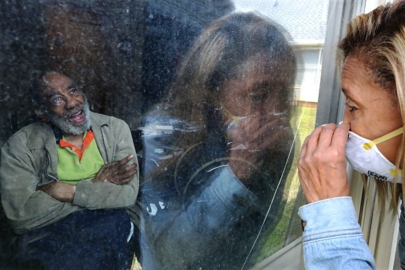 Camilla White becomes emotional while visiting her uncle Eddie Marsh from outside his window at Cottage Landing assisted living in Carrollton on April 28. White didn’t know there had been a significiant outbreak of COVID-19 and several deaths at the home until seeing the information on a state website. White’s mother, Lillian Barber, also lives at the facility. Curtis Compton ccompton@ajc.com