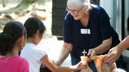 MUST summer lunch program founder Carol Hunt hands out sack lunches to children.