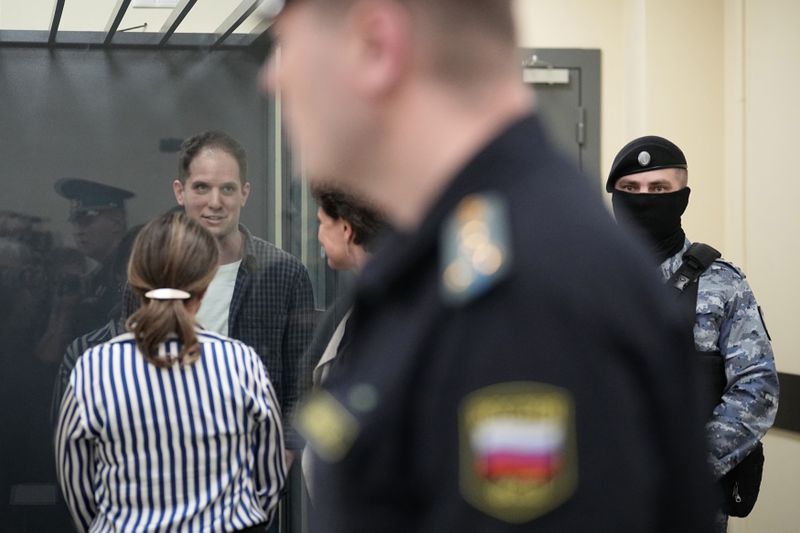 Wall Street Journal reporter Evan Gershkovich speaks with his lawyers standing in a glass cage in a courtroom at the First Appeals Court of General Jurisdiction in Moscow, Russia, Tuesday, April 23, 2024. A court will considers an appeal against the arrest of WSJ reporter Evan Gershkovich who was detained on espionage charges in Yekaterinburg last year. (AP Photo/Alexander Zemlianichenko)