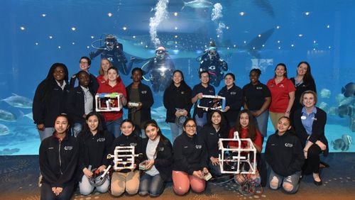 Students from Sweetwater Middle School and instructors pose with divers (from left) Susan Street, Lauren Schwitters and Kristen Binz for a group photograph during Girls Underwater ROV STEM Camp at Georgia Aquarium on Thursday, April 4, 2019. HYOSUB SHIN / HSHIN@AJC.COM