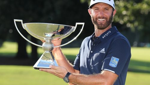 Dustin Johnson is presented the FedEx Cup trophy after sinking his birdie putt on the 18th green to win the Tour Championship and FedEx Cup by three strokes at 21-under par at East Lake Golf Club on Monday, Sept. 7, 2020 in Atlanta. (Curtis Compton / Curtis.Compton@ajc.com)