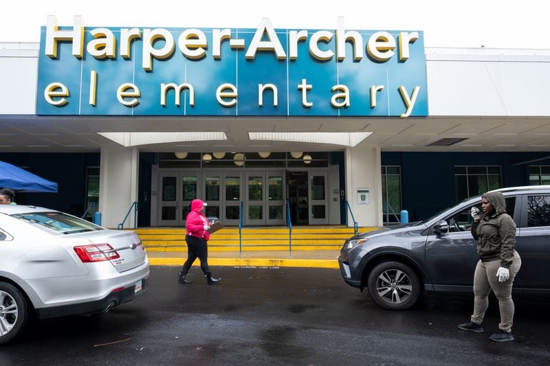 Kydeia Mahaffey-Jones, left, and Diamond Parks, both paraprofessionals at Harper-Archer Elementary School, distribute devices to parents who drove up to the school on March 24, 2020. The school was issuing devices to students so they could continue studying during the coronavirus pandemic. Ben@BenGray.com for the Atlanta Journal-Constitution