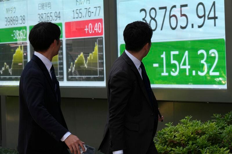 Passersby look at an electronic stock board showing Japan's Nikkei 225 index at a securities firm Friday, May 17, 2024, in Tokyo. (AP Photo/Eugene Hoshiko)