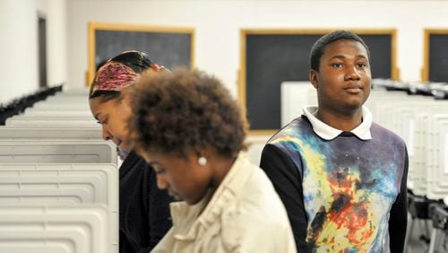 Demarcus Scrubb, 18, right, leaves after casting his ballot Oct. 31. He voted with a group of Columbia High School seniors as a part of their coursework and to build familiarity with the electoral process. (DAVID BARNES / DAVID.BARNES@AJC.COM)