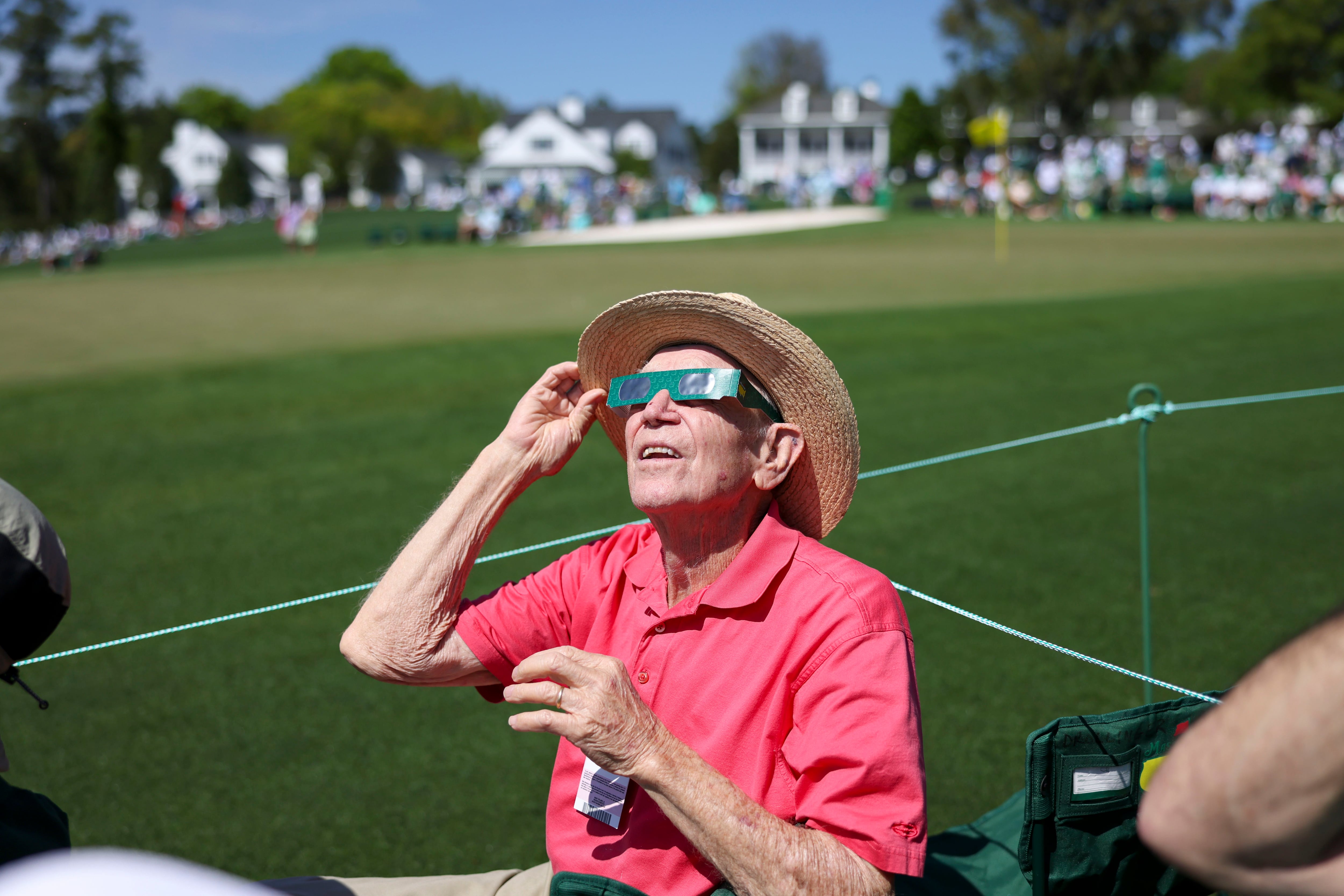 91-year-old Marcus Mooneyhan, of Newport, Tn, uses eclipse glasses to view the solar eclipse on the ninth green during the practice round of the 2024 Masters Tournament at Augusta National Golf Club, Monday, April 8, 2024, in Augusta, Ga. (Jason Getz / jason.getz@ajc.com)