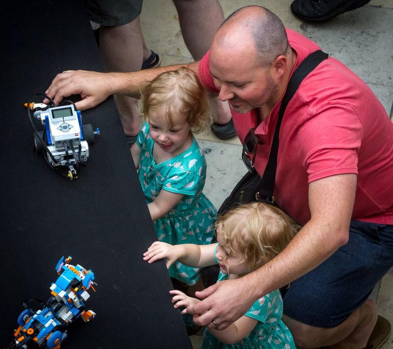 Andrew Kelly looks over some robots with his two girls Joelle and Everett during Robots Day at the Fernbank Museum of Natural History Saturday, June 23, 2018. (STEVE SCHAEFER / SPECIAL TO THE AJC)