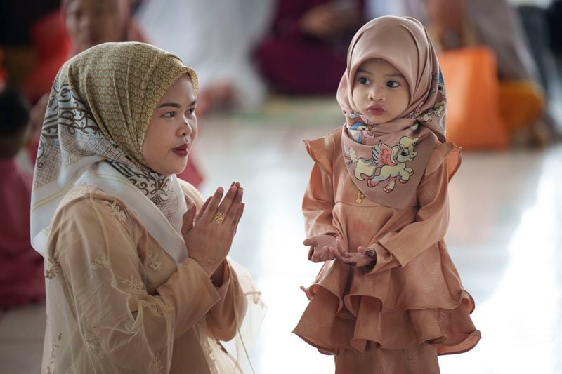 A Muslim woman shows her daughter how to pray as they attend prayers at National Mosque for the Eid al-Fitr, marking the end the holy fasting month of Ramadan in Kuala Lumpur, Malaysia, Wednesday, April 10, 2024. (AP Photo/Vincent Thian)