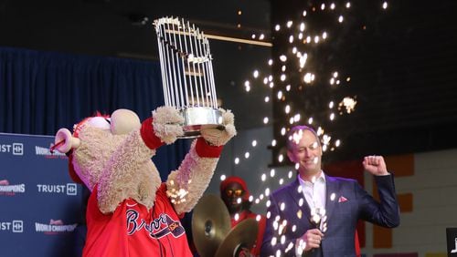 Atlanta Braves mascot Blooper shows the Commissioner’s Trophy to the crowd while Braves President and CEO Derek Schiller reacts during the first stop of the World Champions Trophy Tour on Tuesday at Colony Square in Midtown. (Miguel Martinez for The Atlanta Journal-Constitution)
