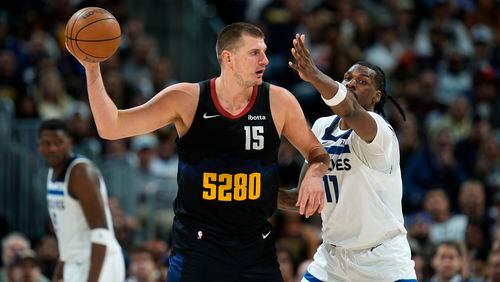 Denver Nuggets center Nikola Jokic, left, looks to pass the ball as Minnesota Timberwolves center Naz Reid defends during the second half of Game 2 of an NBA basketball second-round playoff series, Monday, May 6, 2024, in Denver. (AP Photo/David Zalubowski)