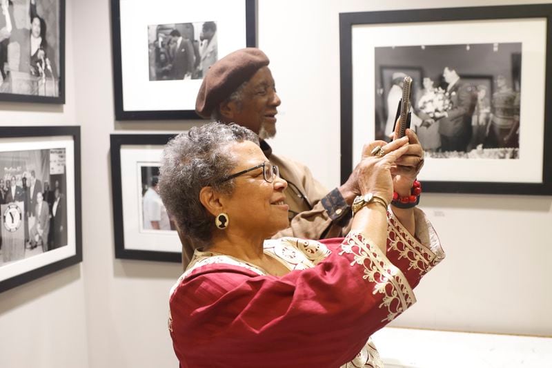 Photographers Susan “Sue” Ross and Jim Alexander take photos with their phones during the reception for their joint exhibition “A Phoenix Reborn” at the Mayor’s Gallery at City Hall on Thursday, Feb. 22, 2024. (Natrice Miller/ Natrice.miller@ajc.com)