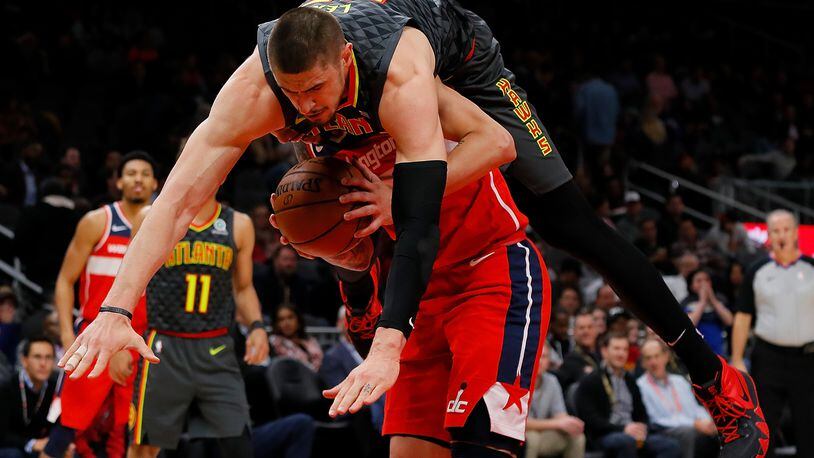 Alex Len (top) of the Hawks is charged with a foul as he falls over Austin Rivers of the Washington Wizards.  (Photo by Kevin C. Cox/Getty Images)