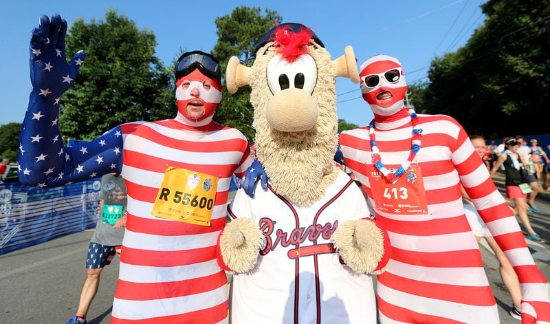 Bryan Fieldman (left) and Mike Walling stop to hug Braves mascot Blooper after finishing the AJC Peachtree Road Race on Wednesday, July 4, 2018, in Atlanta. Curtis Compton/ccompton@ajc.com