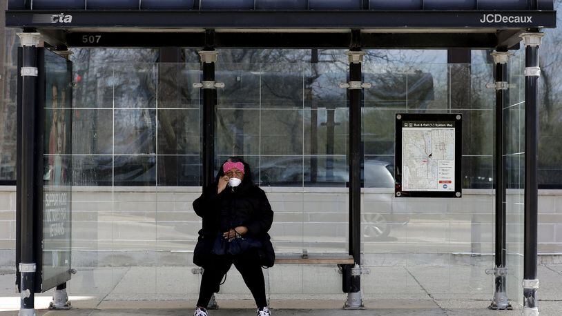 A pedestrian checks her mask as she waits for a bus during the COVID-19 pandemic in Chicago’s Logan Square, Friday, April 10, 2020. AP PHOTO / NAM Y. HUH