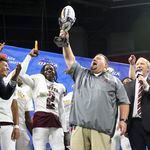 State champions: Coffee head coach Mike Coe lifts the trophy after his team defeated Creekside 31-14 in the Class 5A GHSA State Championship game at Mercedes-Benz Stadium, Wednesday, December. 13, 2023, in Atlanta. (Jason Getz / Jason.Getz@ajc.com)