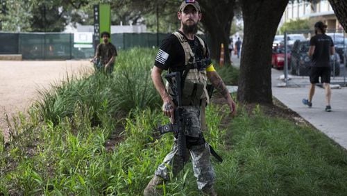 A man openly carrying a long gun walks through plants while watching anti-fascists during a demonstration in downtown Austin, Texas, on Saturday, Nov. 4, 2017. (Photo: Nick Wagner/Austin American-Statesman)
