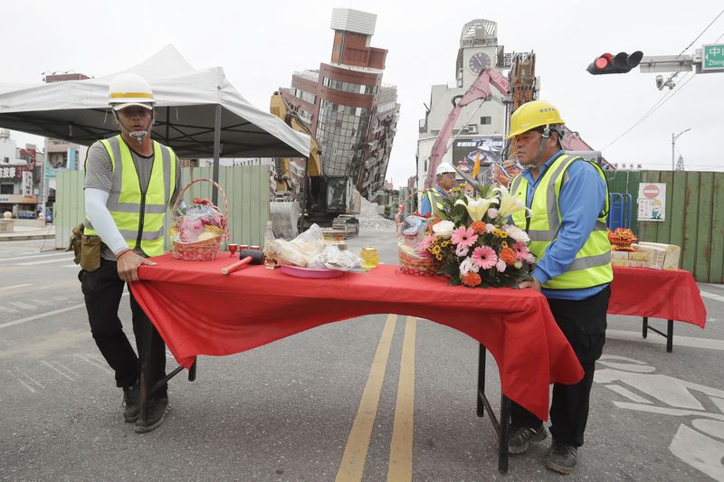 Workers set up offerings before the demolition ceremony in front of the building seen partially collapsed, two days after a powerful earthquake struck the city, in Hualien City, eastern Taiwan, Friday, April 5, 2024. Rescuers searched Thursday for missing people and worked to reach hundreds stranded when Taiwan's strongest earthquake in 25 years sent boulders and mud tumbling down mountainsides, blocking roads. (AP Photo/Chiang Ying-ying)