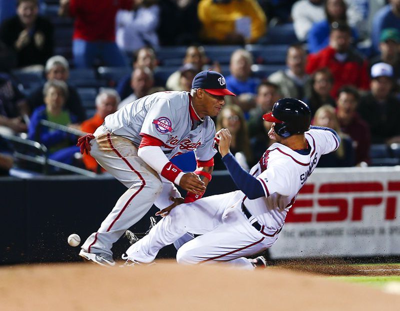 Atlanta Braves' Andrelton Simmons (19) is safe at third base as the ball gets away from Washington Nationals third baseman Yunel Escobar (5) in the fifth inning of a baseball game Monday, April 27, 2015, in Atlanta. Simmons was advancing to third from first base after a wild throw. Escobar was injured on the play and left the game.(AP Photo/John Bazemore) The ball is already out of Yunel Escobar's glove, and Andrelton Simmons still isn't on the ground. (John Bazemore/AP photo)