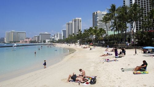 FILE - In this Monday, March 13, 2017, file photo, people relax on the beach in Waikiki in Honolulu. Many Americans might dream of going on vacation to places such as Waikiki, but a new poll shows nearly half of Americans won't be taking a summer vacation this year, mostly because they can't afford it and some because they can't get away from work. (AP Photo/Caleb Jones, File)