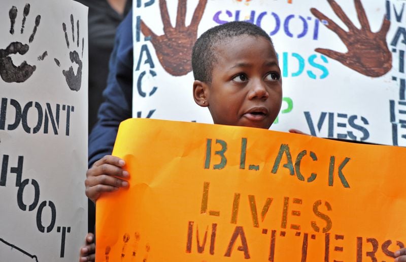 METRO B3 SECONDARY December 6, 2014 Marietta - Marquise Miller, 8, who came with his mother, holds a sign outside Marietta Municipal Court during their peaceful demonstration against decisions not to indict white police officers in the deaths of unarmed black men in Ferguson, Mo., and in New York City on Saturday, December 6, 2014. HYOSUB SHIN / HSHIN@AJC.COM Marquise Miller, 8, holds a sign outside Marietta Municipal Court during a peaceful demonstration earlier this month of police killings of unarmed black men. HYOSUB SHIN /AJC