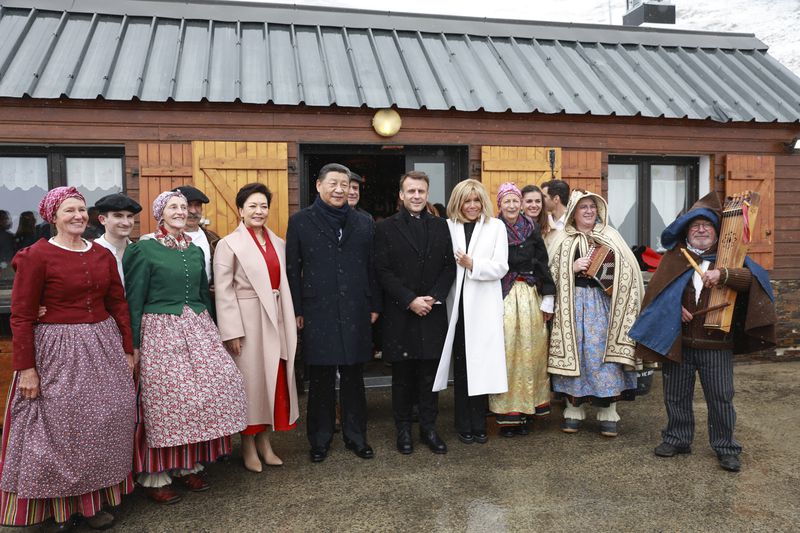 French President Emmanuel Macron and his wife Brigitte Macron, Chinese President Xi Jinping, center left, and his wife Peng Liyuan, fourth left, pose with folklore dancers, Tuesday, May 7, 2024 at the Tourmalet pass, in the Pyrenees mountains. French president is hosting China's leader at a remote mountain pass in the Pyrenees for private meetings, after a high-stakes state visit in Paris dominated by trade disputes and Russia's war in Ukraine. French President Emmanuel Macron made a point of inviting Chinese President Xi Jinping to the Tourmalet Pass near the Spanish border, where Macron spent time as a child visiting his grandmother. (AP Photo/Aurelien Morissard, Pool)