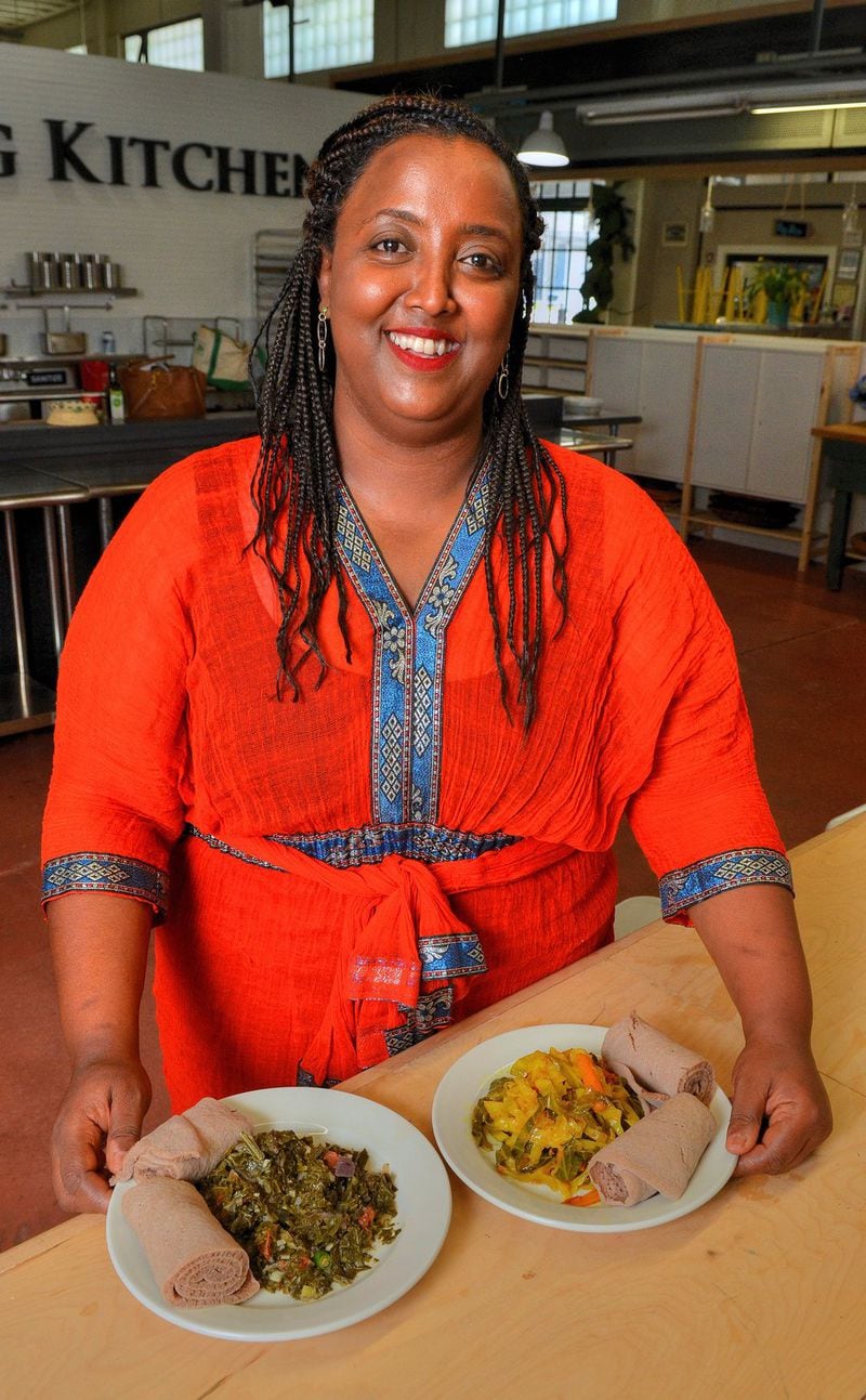 Yohana Solomon of Kushina Catering poses with the two dishes she shared: (from left) Gomen (Collard Greens) and Tekel Gomen (Cabbage and Carrots), both with the traditional bread injera. Solomon is from Ethiopia, but her parents are from Eritrea. She’s shown at the Learning Kitchen facilities inside the Sweet Auburn Curb Market in downtown Atlanta. STYLING BY YOHANA SOLOMON / CONTRIBUTED BY CHRIS HUNT PHOTOGRAPHY