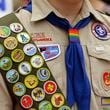 FILE - Merit badges and a rainbow-colored neckerchief slider are affixed on a Boy Scout uniform outside the headquarters of Amazon in Seattle. The U.S. organization, which now welcomes girls into the program and allows them to work toward the coveted Eagle Scout rank, announced Tuesday, May 7, 2024, that it will change its name to Scouting America as it focuses on inclusion. (AP Photo/Ted S. Warren, File)