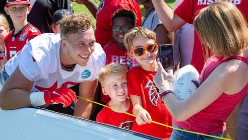 Durrant Miles (from left) climbed the barrier for a photo with Ben Hair, 6, and his brother Henry, 8, taken by Cate Cranston after working out with the Atlanta Falcons Football team during practice camp in Flowery Branch on Thursday July 25th, 2019. Phil Skinner/For the AJC