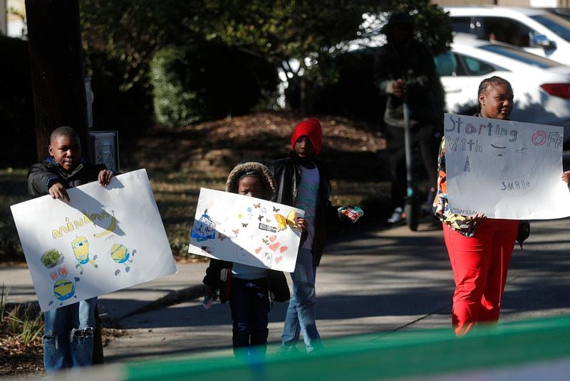 Kids hold up signs along the parade route during the annual Martin Luther King, Jr. Day Parade on Monday January 16, 2023.