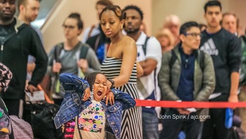 Milani Kinos, 4, with mother Michelle Rustin wait in long lines at Hartsfield-Jackson International Airport Thursday as the Memorial Day travel holiday is underway. Photo: JOHN SPINK /JSPINK@AJC.COM