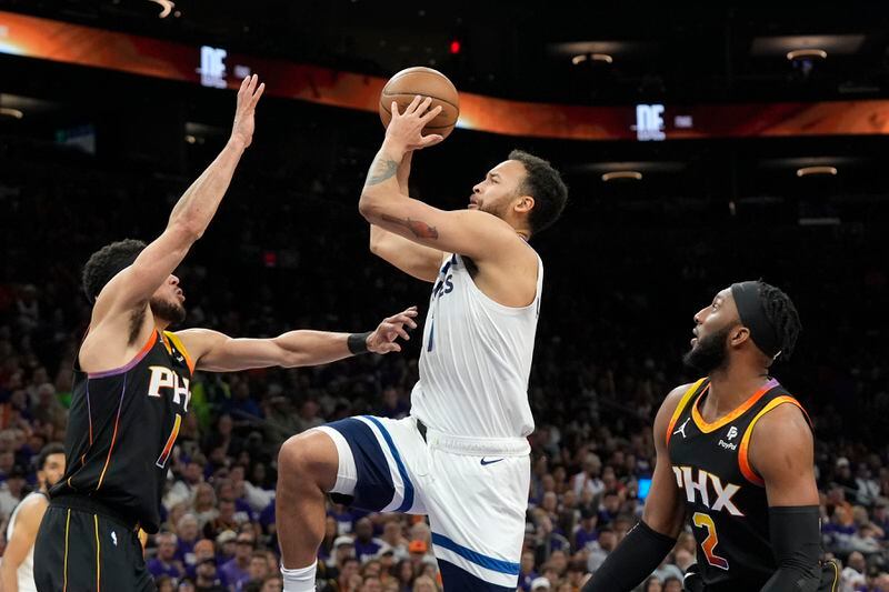 Minnesota Timberwolves forward Kyle Anderson, center, gets past Phoenix Suns forward Josh Okogie and Suns guard Devin Booker for a shot during the first half of Game 4 of an NBA basketball first-round playoff series, Sunday, April 28, 2024, in Phoenix. (AP Photo/Ross D. Franklin)
