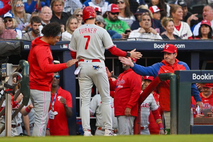 Philadelphia Phillies’ Trea Turner (7) is welcomed to the dugout after scoring against the Atlanta Braves on an RBI single by Alec Bohm during the first inning of NLDS Game 2 in Atlanta on Monday, Oct. 9, 2023.   (Hyosub Shin / Hyosub.Shin@ajc.com)