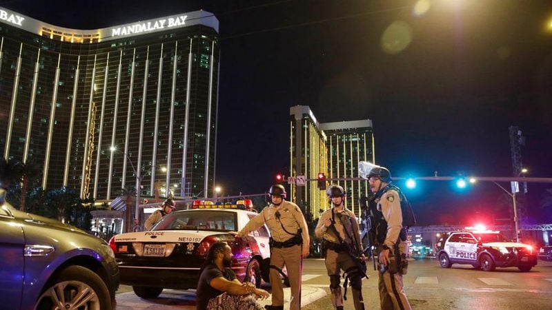 Police officers stand at the scene of a shooting near the Mandalay Bay resort and casino on the Las Vegas Strip, Sunday, Oct. 1, 2017, in Las Vegas. Multiple victims were being transported to hospitals after a shooting late Sunday at a music festival on the Las Vegas Strip.  (AP Photo/John Locher)