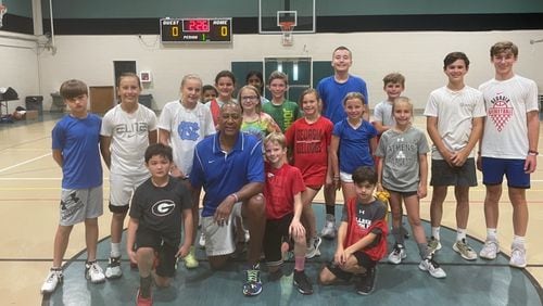Former Georgia basketball great James Banks (center), star of the Bulldogs' run to the Final Four in 1983, poses with the young attendees of his annual youth camp held this week at Beech Haven Baptist Church in Athens. (Photo provided to Chip Towers/ctowers@ajc.com)