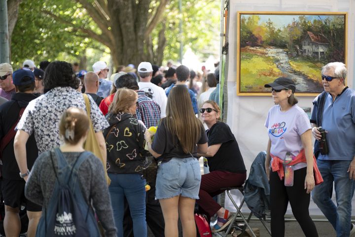 Dawn Kinney Martin, center, who lives in Midtown, smiles at guests while working her painting booth at the Dogwood Festival in Piedmont Park on Saturday, April 13, 2024.   (Ben Gray / Ben@BenGray.com)