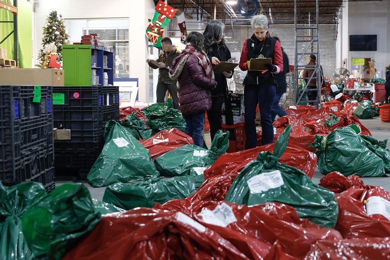 Volunteers fill bags with toys and supplies at the Empty Stocking Fund warehouse in Atlanta on Wednesday, December 21, 2022. (Natrice Miller/natrice.miller@ajc.com)  