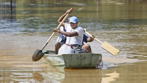 Earl Knight uses a shovel as an oar as rows down the still flooded Oglesby Road in Powder Springs with Cornell Daniels in September 2009. Bob Andres, bandres@ajc.com