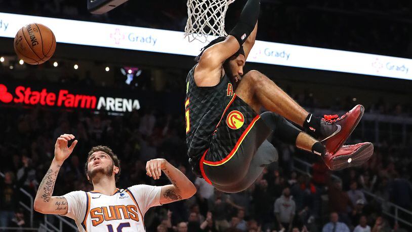 Hawks guard DeAndre' Bembry goes in for a reverse slam over Phoenix Suns guard Tyler Johnson.    Curtis Compton ccompton@ajc.com