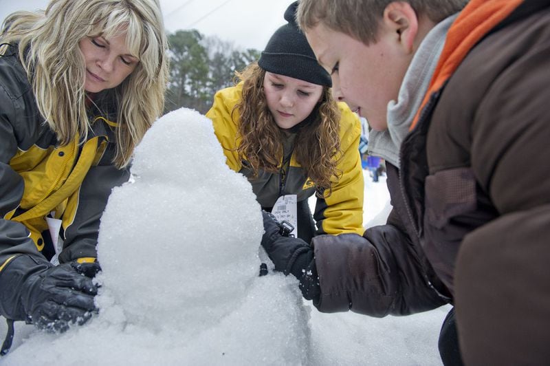 In this 2014 photo, Stephanie Basile (left) builds a snowman with her grandchildren Savanna and C.J. Simpson during Snow Mountain at Stone Mountain Park. JONATHAN PHILLIPS / SPECIAL