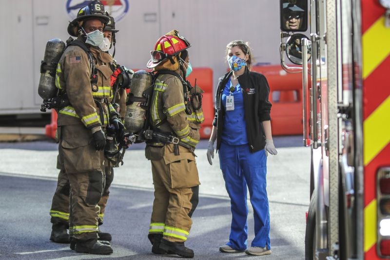 Atlanta Firefighters wear masks as a precaution under the COVID-19 work environment as they speak with a Grady Memorial Hospital critical care nurse outside the Emergency Room at Grady in Atlanta following a full hazardous materials call on Thursday, April 16, 2020. JOHN SPINK/JSPINK@AJC.COM